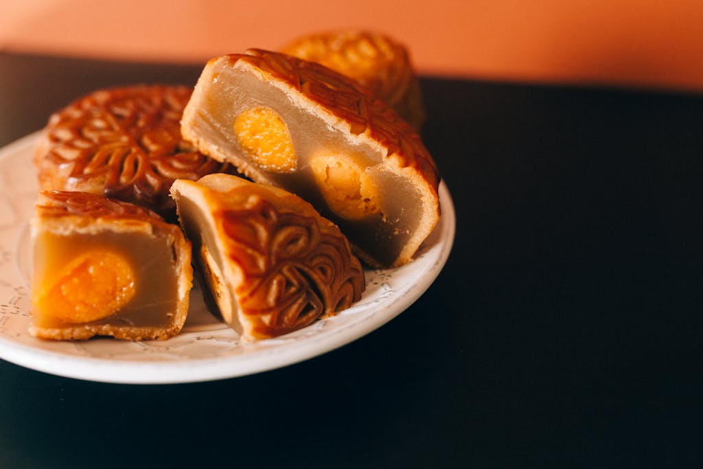 Close-up of traditional Chinese mooncakes with egg yolk filling on a saucer.